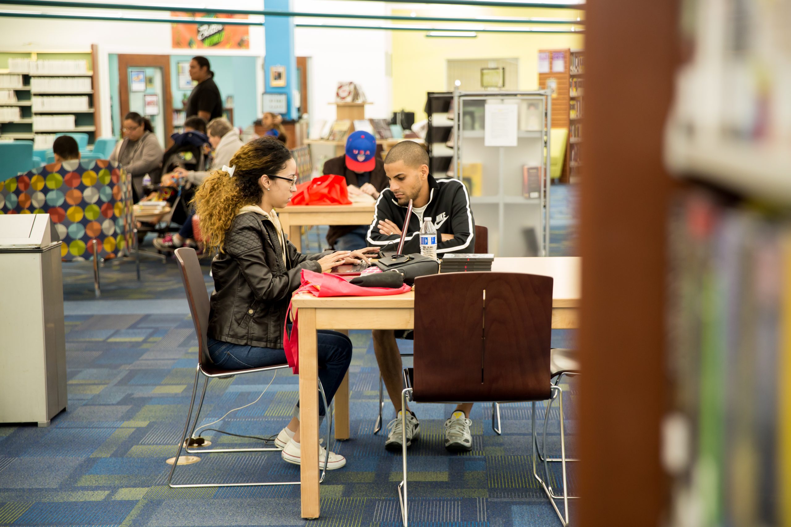 The main area of Poinciana Library, with several groups of patrons working at tables.